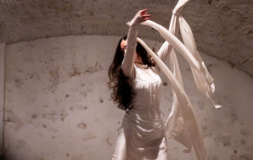 Una scena dell'opera ExClausura in cui una ballerina vestita di bianco sta ballando